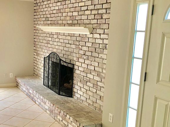 A whitewashed brick fireplace creates a welcoming family/din