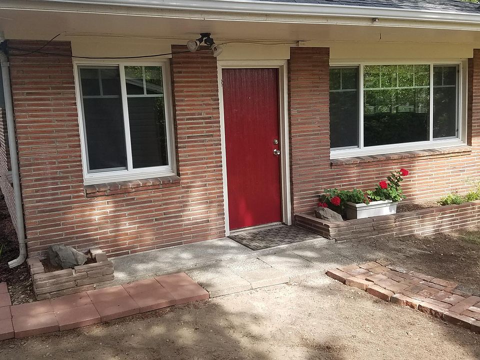 The front door sits beneath a small covered porch surrounded by mature fir trees. A few steps lead up to the entry, where a cheerful door welcomes you into this quiet, private cottage.