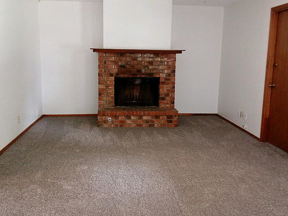 Living area showing fireplace with new carpet. Door going t