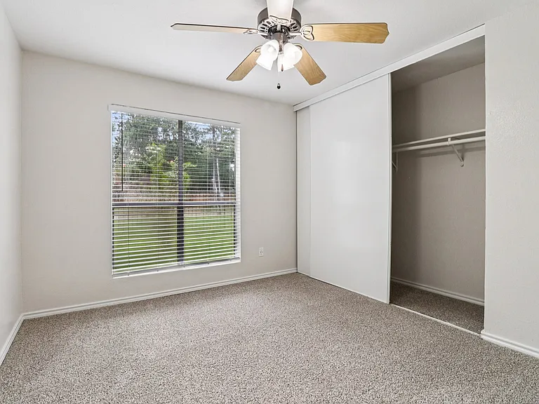 Bright bedroom with plush carpeting, large window with garden view, and spacious closet. Bright bedroom with plush carpeting, large window with garden view, and spacious closet.