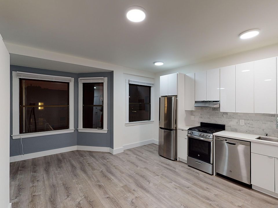 Kitchen with multiple cabinets, refrigerator, stove, range hood, and sink
