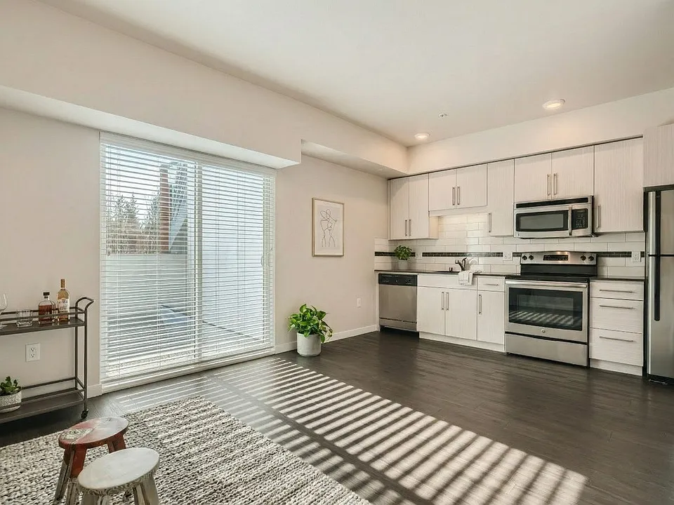 Open-concept layout featuring a modern kitchen with stainless steel appliances, dark flooring, and sliding door access at 306 Queen Anne.