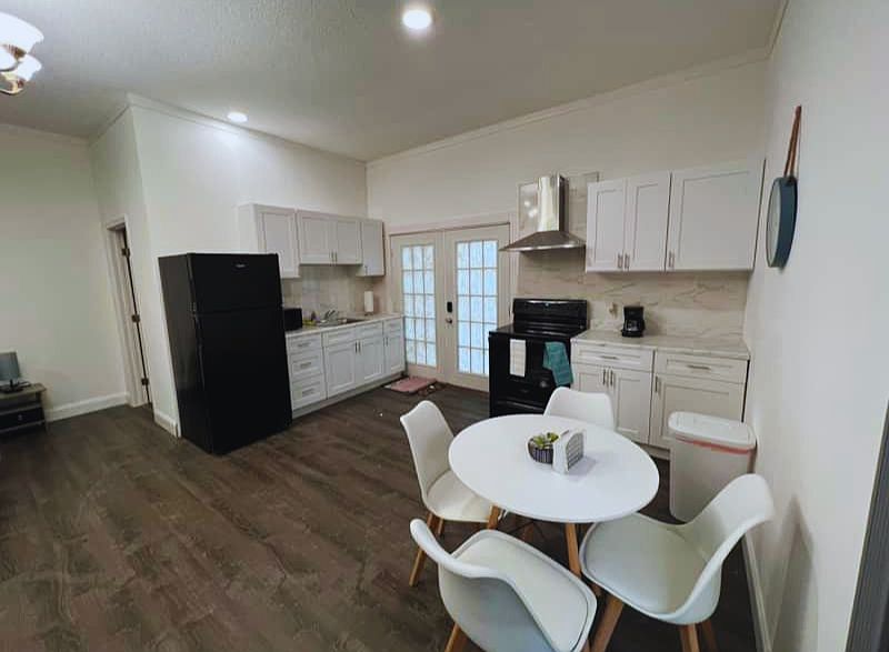 Spacious kitchen & dining with stove, fridge, cabinets, and range hood.
