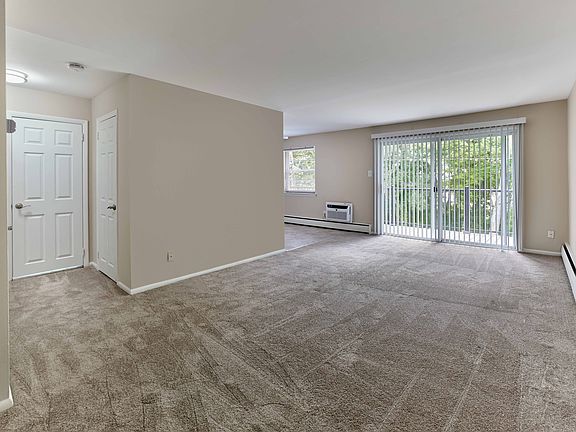 Expansive living area with wall-to-wall carpet and private balcony at Maple Terrace Apartments in Maple Shade, NJ
