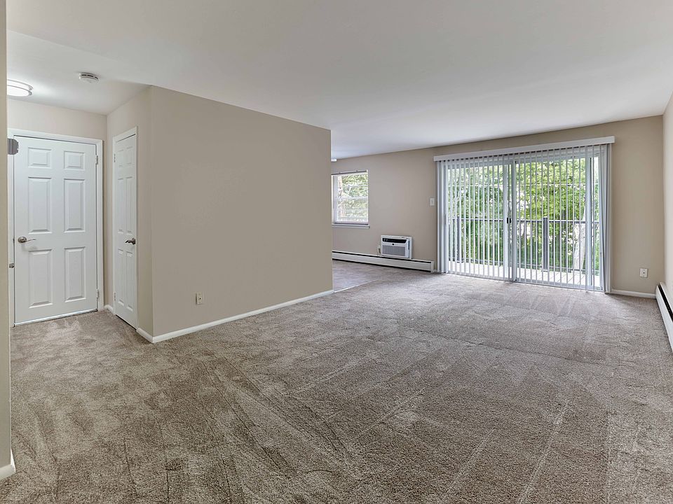 Expansive living area with wall-to-wall carpet and private balcony at Maple Terrace Apartments in Maple Shade, NJ
