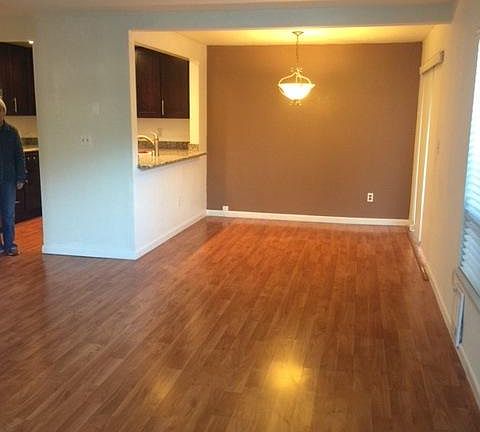Spacious open-design living room, dining area and kitchen with gleaning wood floors, great for relaxing and entertaining - open to private patio
