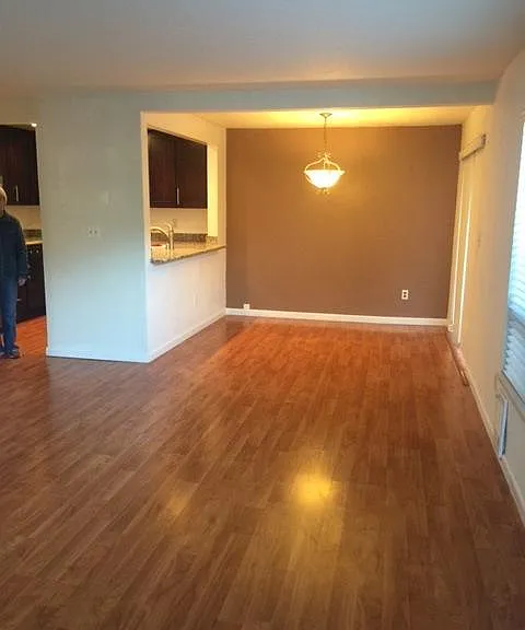 Spacious open-design living room, dining area and kitchen with gleaning wood floors, great for relaxing and entertaining - open to private patio