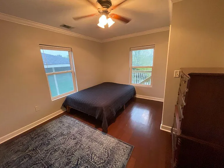Primary bedroom corner with two windows providing strong natural light.