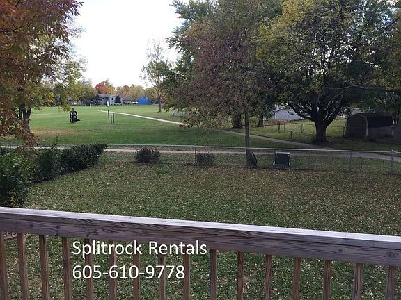 Deck overlooking fenced backyard and private park with playground equipment and walking trails.