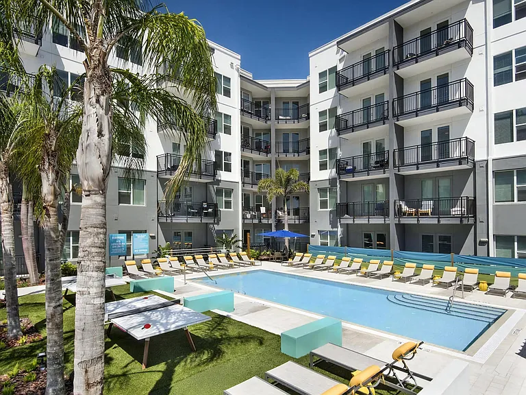Courtyard Pool Surrounded by Lounge Chairs, Ping Pong Tables, and Palm Trees