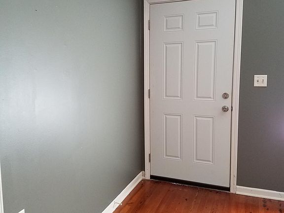 Front door coming into the living room with natural wood floors.