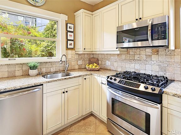 Tuscan style kitchen with gas range, stainless appliances, granite counters, custom cabinetry and ceramic tile floors. Perfectly situated window onto the private backyard 