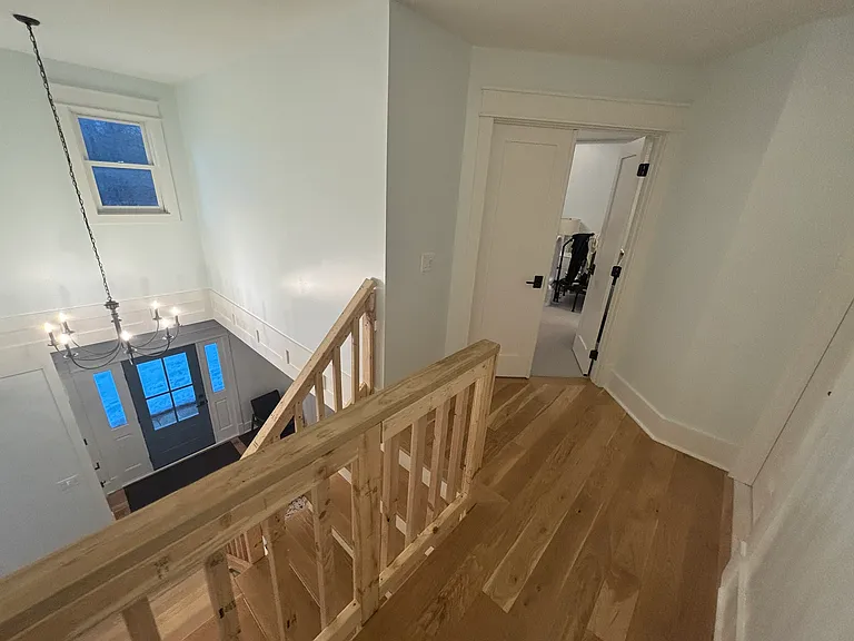 Open stair case with primary bedroom in background.