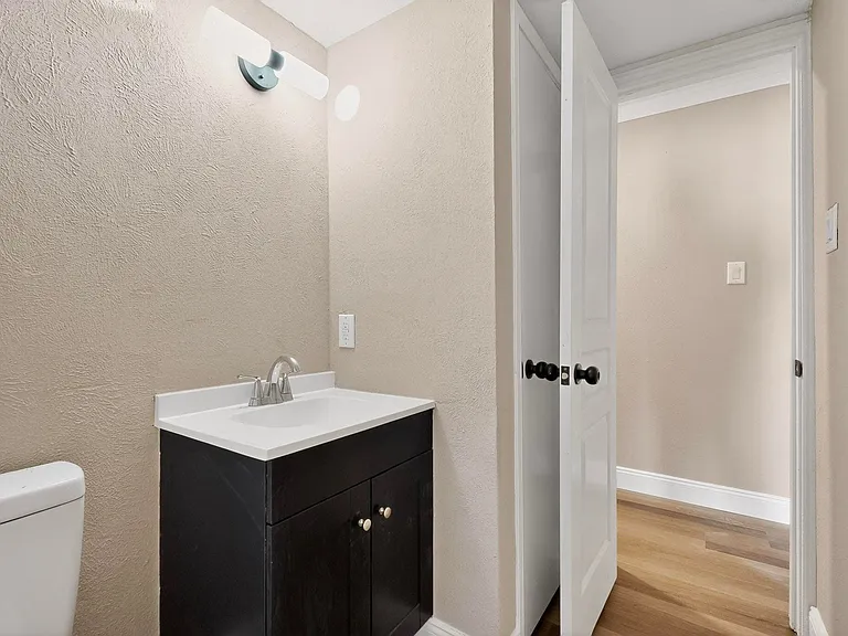 Half bathroom featuring vanity, light wood-style flooring, and a textured wall