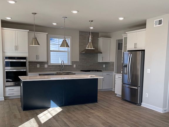 Open kitchen with white cabinets and blue island at a DRB Homes Newbury II plan at the Barron Height