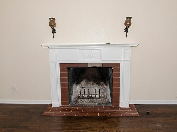 Living room fireplace with mantle, sconces, brick hearth, and gas starter.