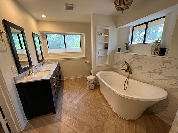 Newly renovated luxe bathroom with soaker tub, double marble and navy vanity, makeup table with built-in lighting, and walk-in shower with rain, handheld, and traditional showerheads