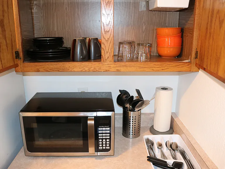 Cupboard with dishes, cups, plates, bowls, utensils. Also (not pictured) pots and pans and cookware in lower cupboard.