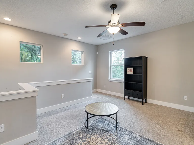 Unwind, watch a movie, or gather for game night. This expansive view of the upstairs loft highlights a cozy, fully furnished entertainment area complete with a cooling ceiling fan, pullout queen sleeper sofa and plenty of natural sunlight