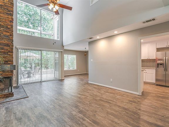 The home has a wall of windows and soaring ceilings! This is a large living space! The gorgeous stacked stone fireplace is a focal point in the room!