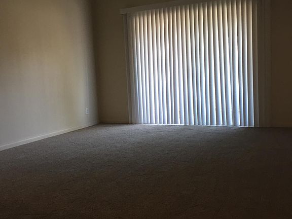 Carpeted living room looking toward spacious balcony outside