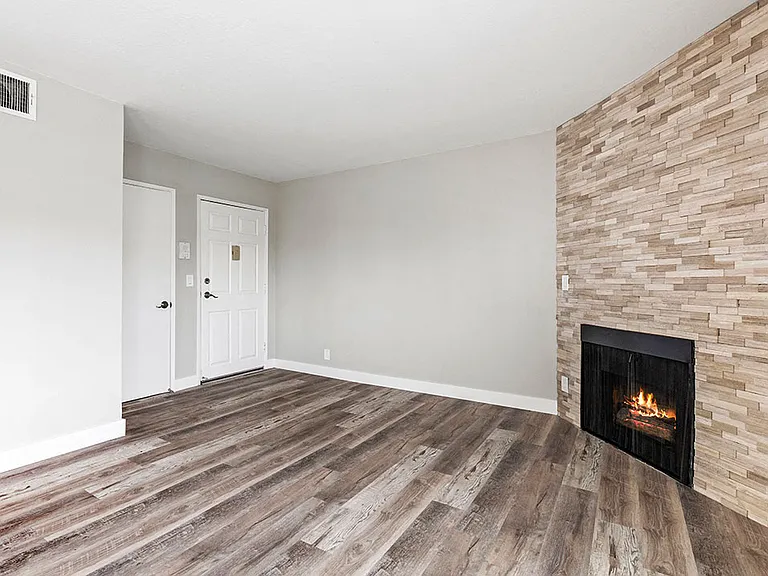 Hardwood floored living room with stone accented fireplace.