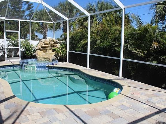 Salt water pool and spa in a large caged area with brick pavers