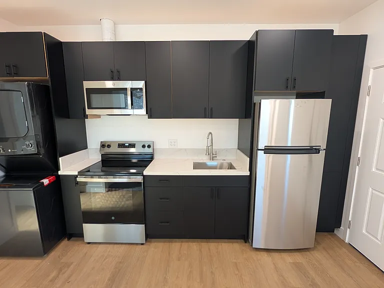 Kitchen with laundry and refrigerator. Electric oven and range with microwave above.