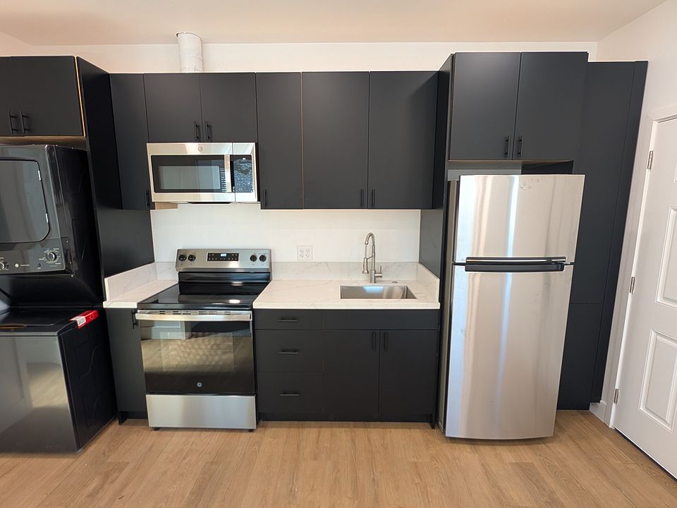 Kitchen with laundry and refrigerator. Electric oven and range with microwave above.