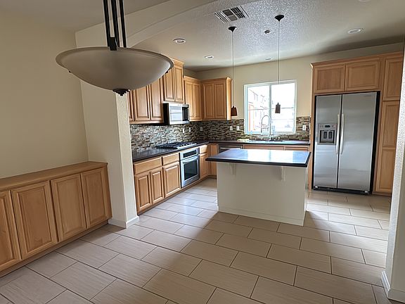 Open concept kitchen and dining with stainless steel Kitchen Aid appliances and lots of storage