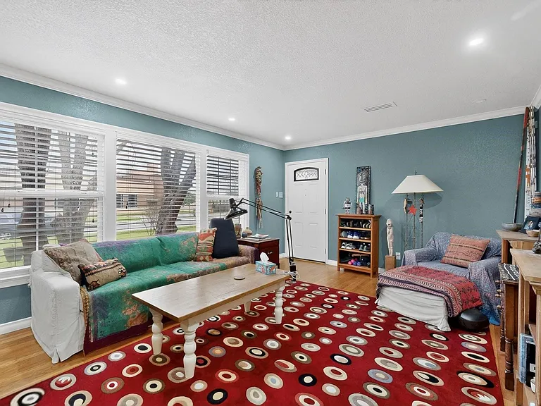 A bright living room with tall, wide windows and hardwood floor, adding warmth to the space.