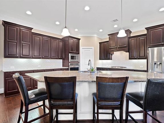 Large kitchen with lots of cabinetry, oversize counter with granite, stainless steel appliances and walk-in pantry.