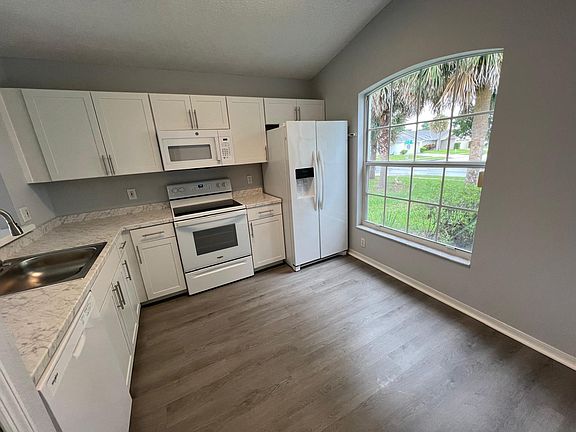 Spacious kitchen with large window, new laminate flooring, recently updated cabinets, and included appliances (side-by-side refrigerator, stove, microwave, and dishwasher).