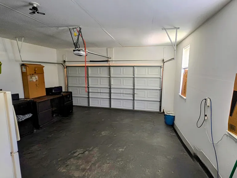 Massive, ultra-clean attached garage offering secure parking, expansive workshop space, and an extra refrigerator.
