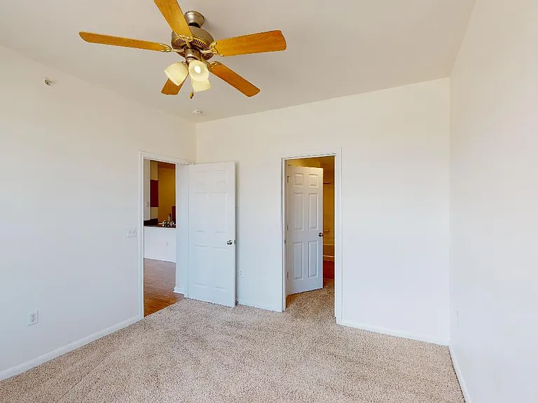 Spacious apartment bedroom with attached bathroom and plush carpet flooring.