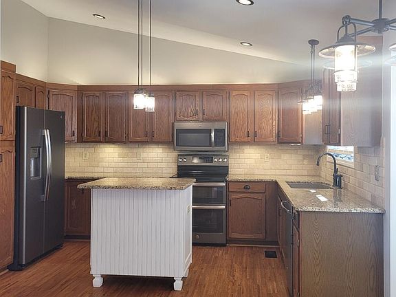 Kitchen features lots of wood cabinets, granite counter tops, stainless appliances and island for extra storage/breakfast bar.