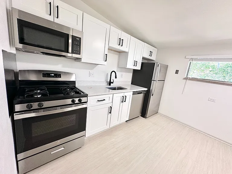 Modern kitchen with sleek stainless steel appliances, elegant white cabinetry, and ample natural light.