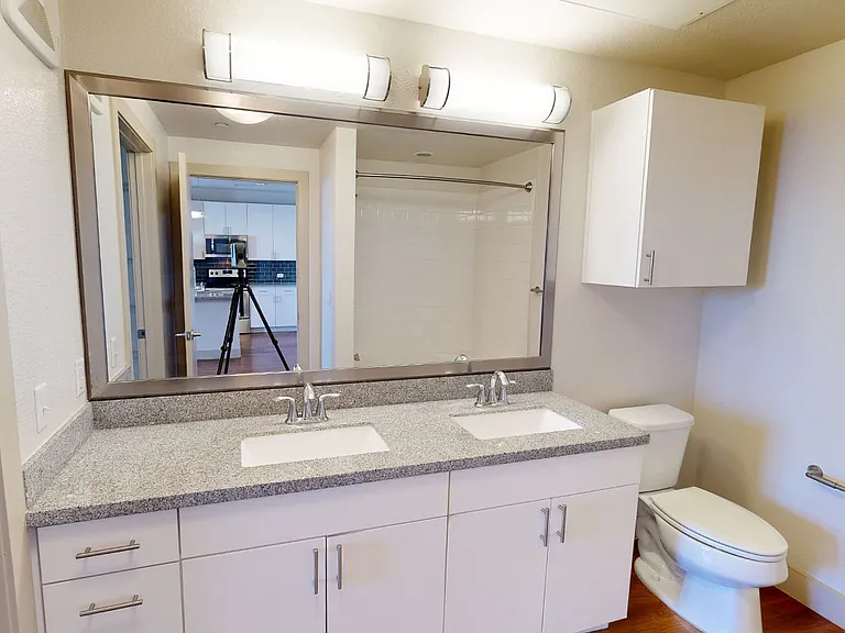 Apartment bathroom with wood-style flooring and double sinks.