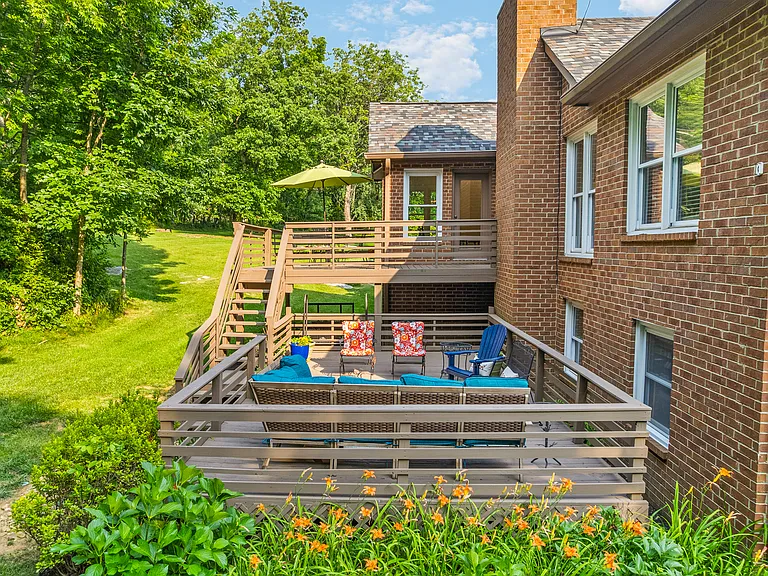 An upper patio and lower deck with beautiful views of the private, wooded backyard.