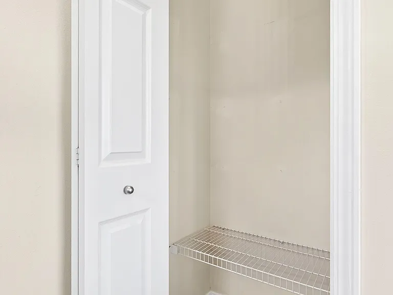 Dedicated closet with hanging rod and wire shelf provides practical storage for clothes, shoes, and luggage.