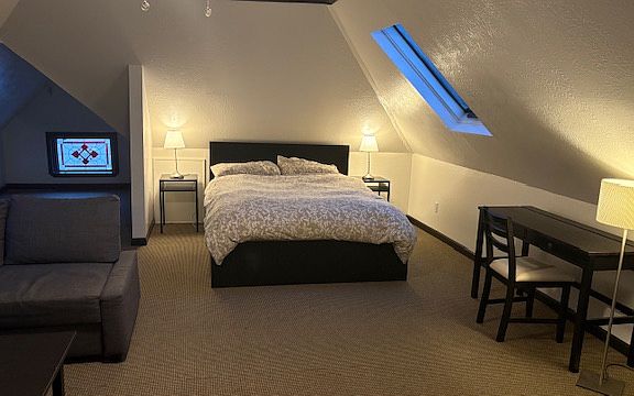 Main room, queen bed with drawers below, bed side tables, lamps, desk and fold out couch