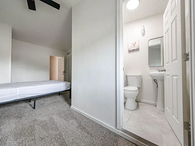 Private bedroom with carpeted floors and ceiling fan, plus an adjacent half bath for added convenience.