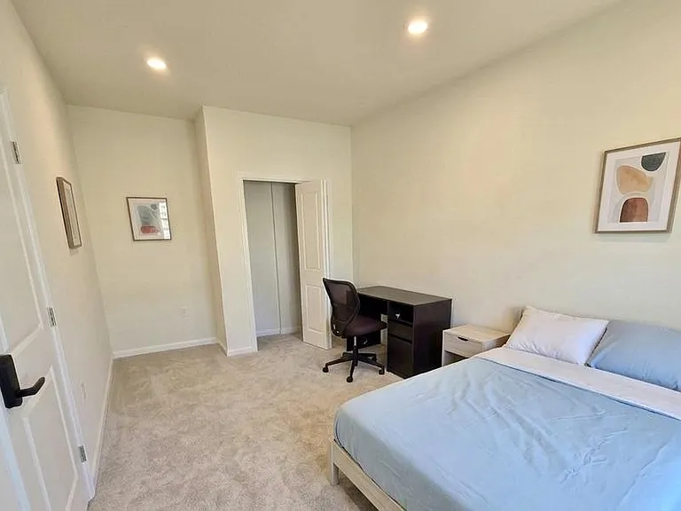 Spacious bedroom with soft carpet, recessed lighting, and a dedicated desk area plus closet storage for everyday convenience.