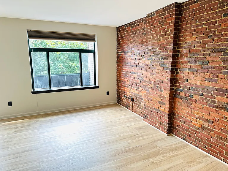 Living room overlooking deck with large picture window and brick wall.