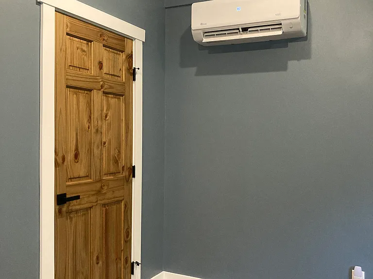 Main level master bedroom with mini-split heating and cooling and vaulted ceiling and a door to porch.