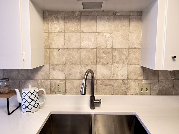 Stainless kitchen sink and faucet. New 2025 white quartz counters with tile backsplash.