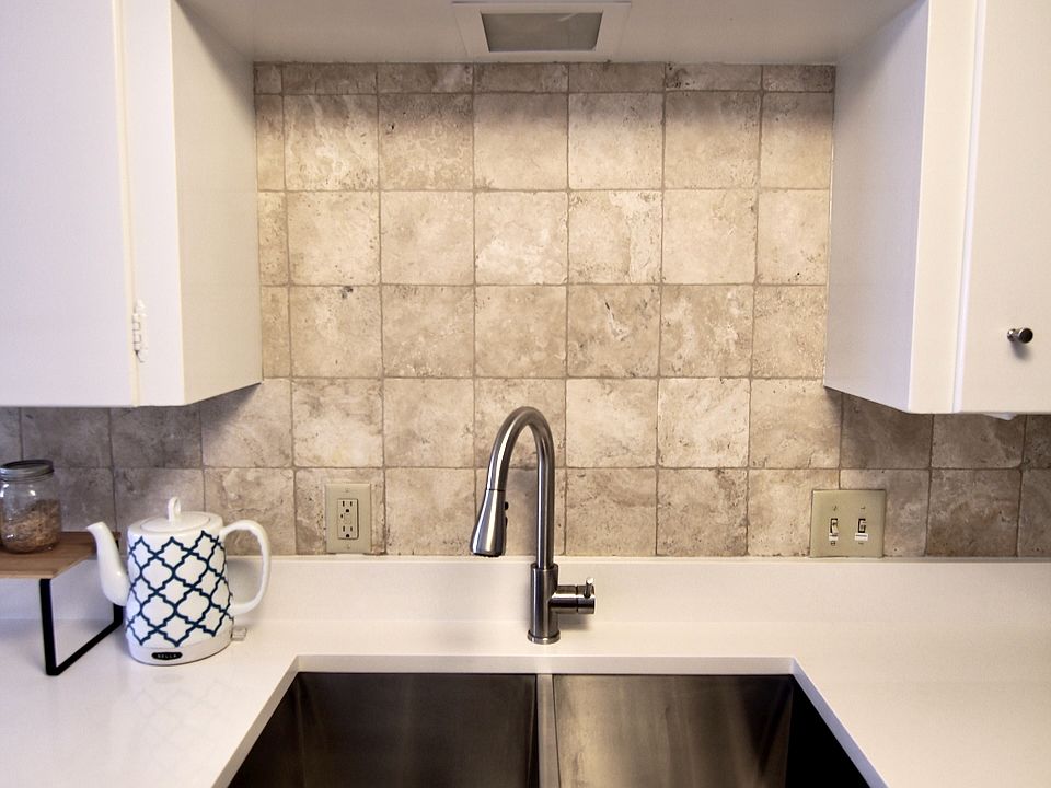Stainless kitchen sink and faucet. New 2025 white quartz counters with tile backsplash.