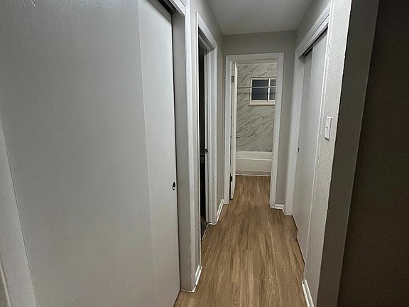 Inviting hallway with sleek wood flooring and modern recessed lighting, offering access to multiple rooms.