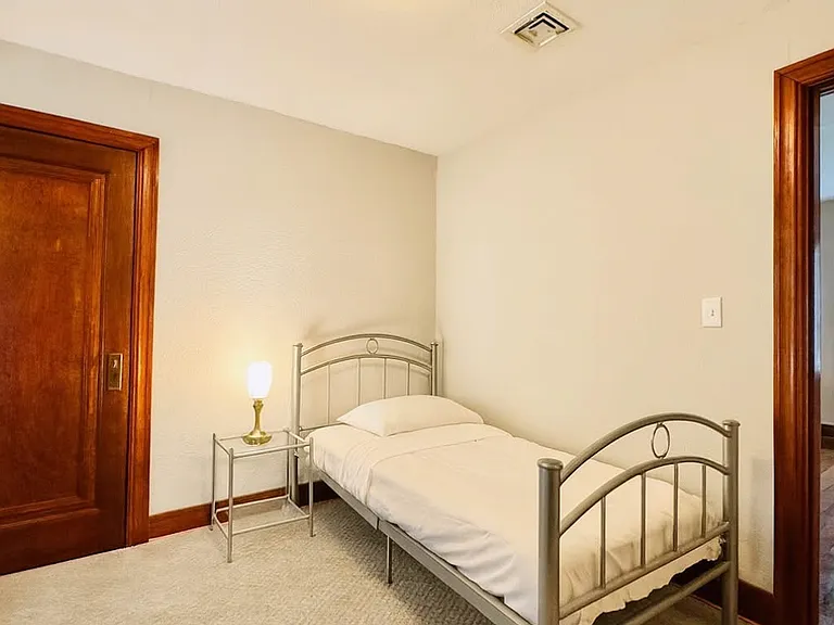 Cozy bedroom with a large glass window overlooking the driveway, bringing in natural light and fresh air. Includes a convenient walk-in closet. Carpeted flooring helps maintain warmth and comfort during winter months. Ideal for a peaceful retreat.