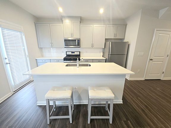 Kitchen with large quartz island, SS fridge, 5-burner gas stove and walk-in pantry